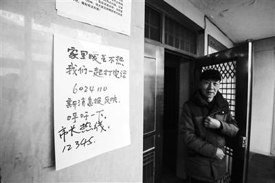 建安小区8号楼1单元门口贴着市长热线、新消息报新闻热线电话。