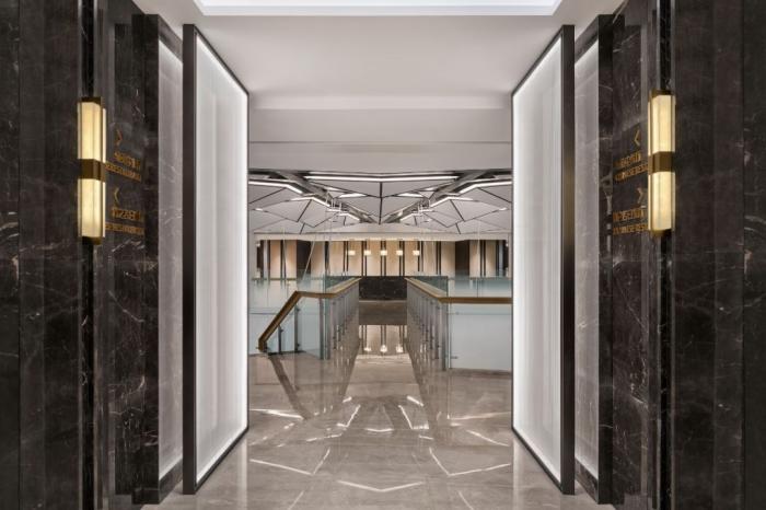电梯厅给人以时空隧道般的未来感，空间尽头的组合灯饰延用了大堂的抽象齿轮元素。